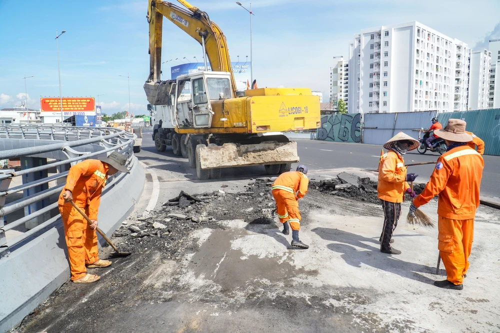 Công nhân bóc tách lớp bê tông nhựa tại vị trí sụt lún ở dự án nút giao thông Ngọc Hội. Ảnh: XUÂN HOÁT Tập đoàn Phúc Sơn.jpg