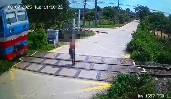 Người đàn ông đứng giữa đường ray khi tàu hỏa đang đi tới. (Ảnh cắt từ clip)