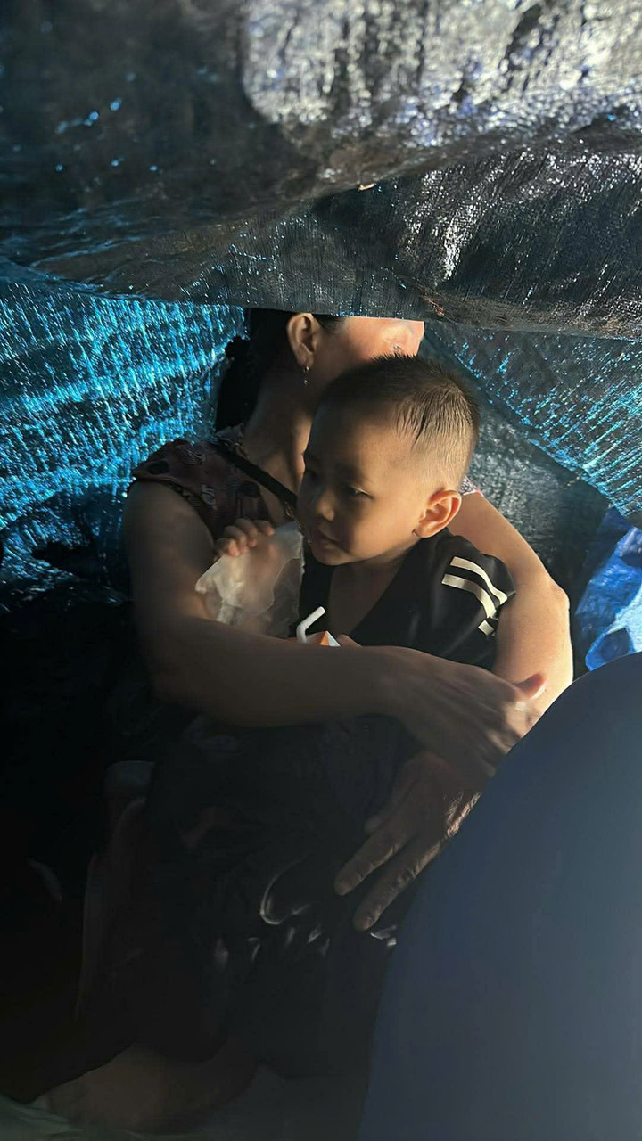 Một em bé co ro trên mái nhà giữa cơn lũ.